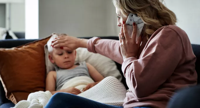 Mother with hand on child's forehead calling her doctor for expert medical advice