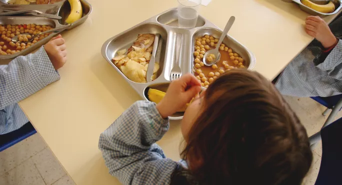 Child from above eating beans on tray