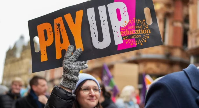 Woman holding sign saying "pay up"