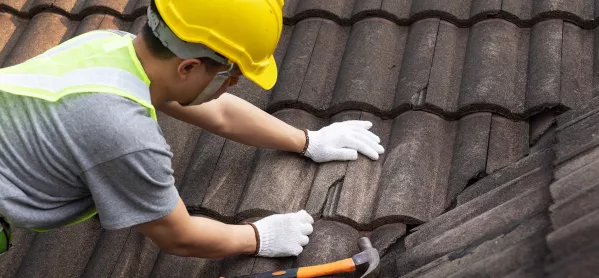 A man wearing a hard hat fixing a roof