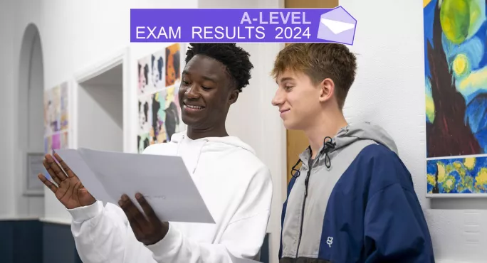 Two teenage boys opening a results envelope