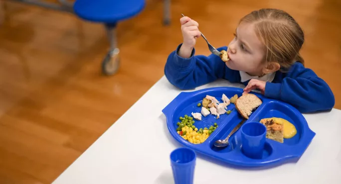 Child sat eating with school lunch tray