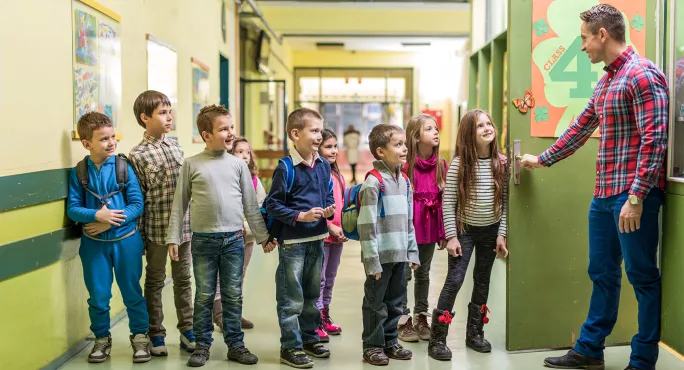 Teacher welcoming pupils to class