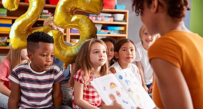 Teacher with class with number 25 balloons