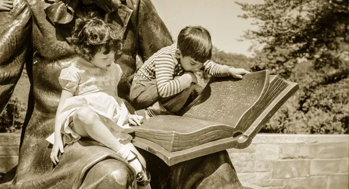 Two children reading a book on a statue