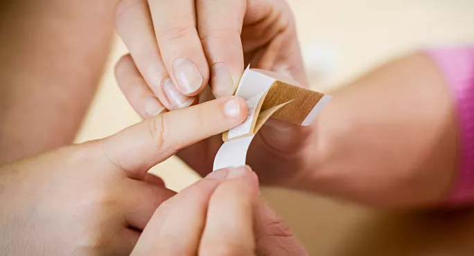 Applying a band aid to child's finger