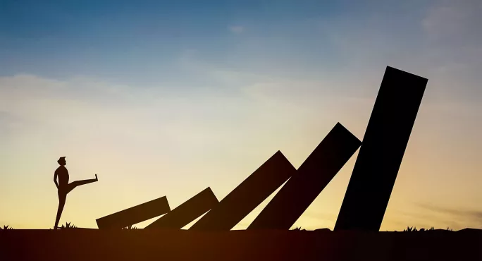 Illustration of someone kicking down giant dominos