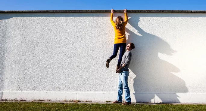 Boy helping a girl over a wall