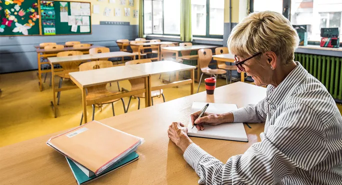 Teacher alone at her desk marking papers