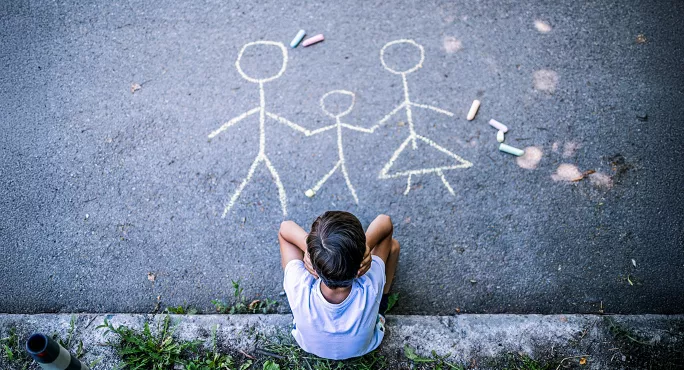 Child looking at chalk drawing of a family