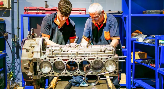 Two men fixing an engine