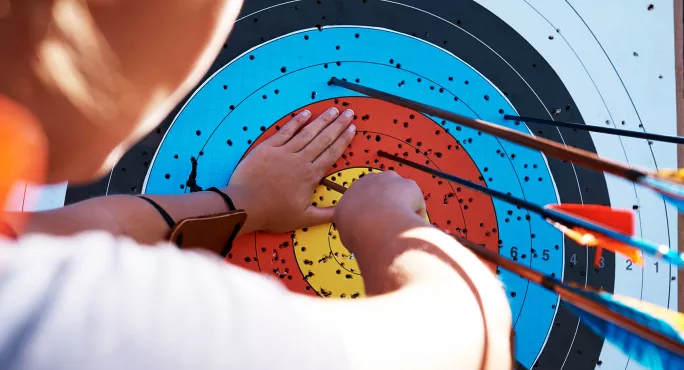 Child pulling arrows out of target board
