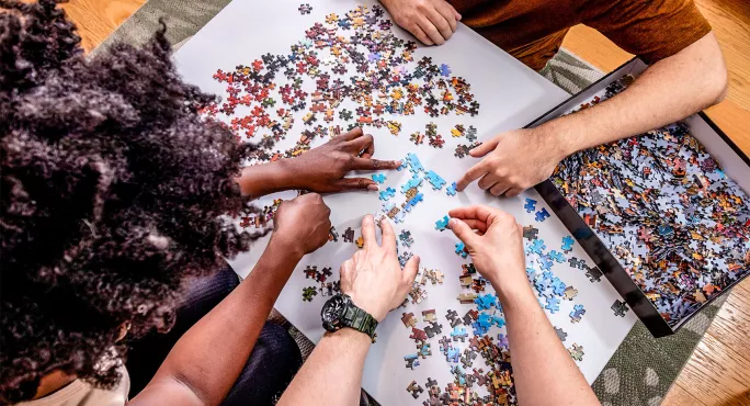 Several hands putting together puzzle pieces