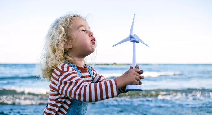Small child blowing on windmill Sustainability Scotland