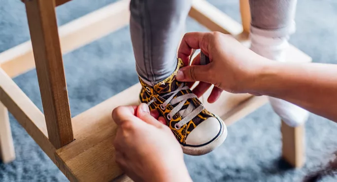 Mother tying child's shoes School Ready