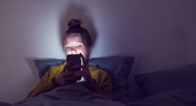 Young girl in bed on phone