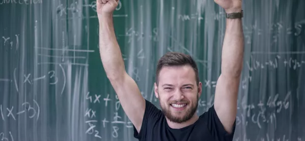 Teacher Raising Hand In Cheer, In Front Of Blackboard