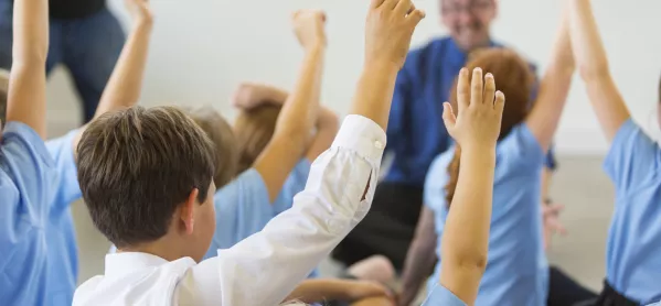 Children In Classroom, With Hands Raised