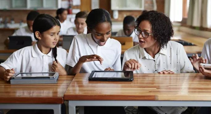 Children Looking At Content On A Tablet In The Classroom