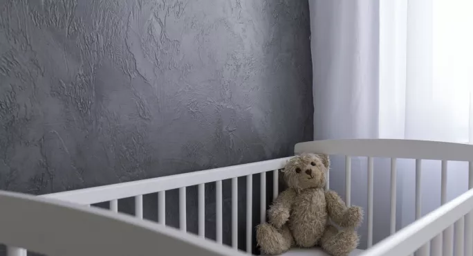 Empty Cot, With Teddy Bear In Corner