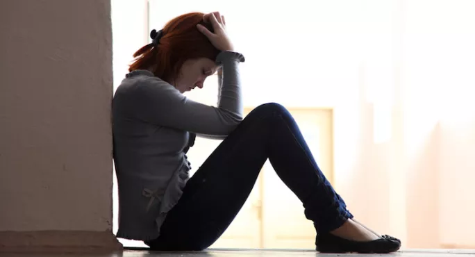 Teenage Girl, Slumped Against A Wall In Despair