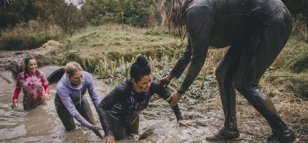 People Helping One Another Out Of A Muddy Pond