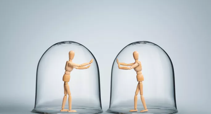 Two Wooden Figures, Enclosed By Separate Bubbles, Try To Touch On Another