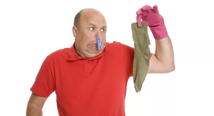 Man With Clothes Peg On His Nose Holds Up Crusty Sock