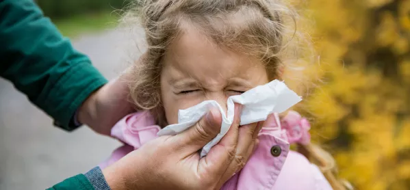 Small Schoolgirl Sneezes Into Tissue Held By Her Father