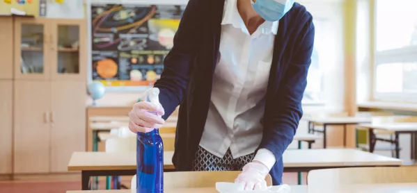 Teacher, In Face Mask, Disinfects Classroom Table