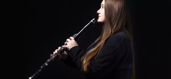 Teenage Girl Plays The Clarinet, Against Dark Background