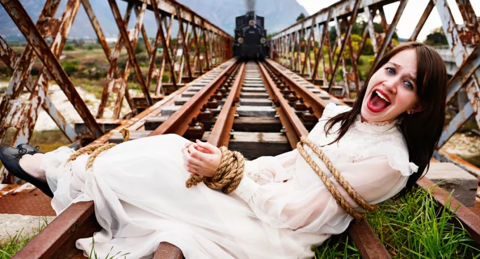 Woman Tied To Rail Tracks, While Steam Train Approaches In The Distance