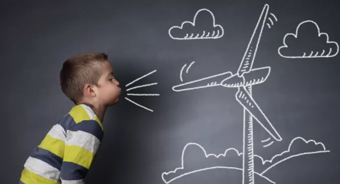Child Blowing Into A Wind Turbine On Blackboard
