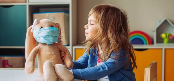 Young Girl At Nursery School Plays With A Cuddly Rabbit That's Wearing A Face Mask
