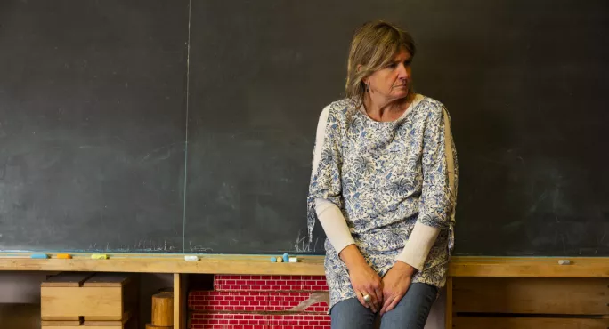 Teacher Standing In Front Of Blackboard Looking Stressed