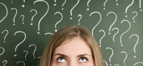 Woman Standing In Front Of Blackboard, On Which Question Marks Are Drawn