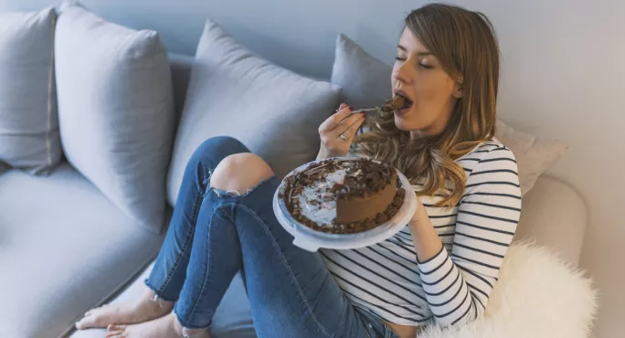 Woman Sitting On The Sofa, Eating A Whole Chocolate Cake