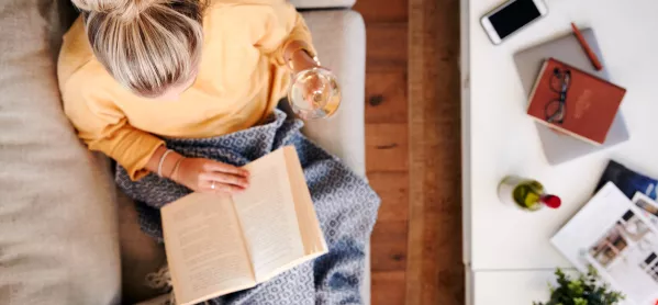 Overhead Shot Of Woman, Sitting On Sofa With A Book, A Glass Of Wine, & A Blanket Over Her Legs
