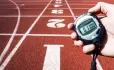 person holding timer showing 11 minutes against backdrop of athletics track