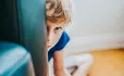 child peeping out from behind chair