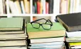 A pair of glasses on top of three piles of books