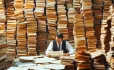 Man sitting at desk with loads of papers