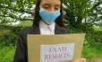 Girl In Face Mask Holds Envelope Labelled "exam Results"