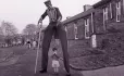 Man Wearing Stilts With Child Between Legs
