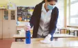 Teacher, In Face Mask, Disinfects Classroom Table