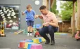 Teacher Holds Hand Of Small Boy, Jumping On Upturned Pots